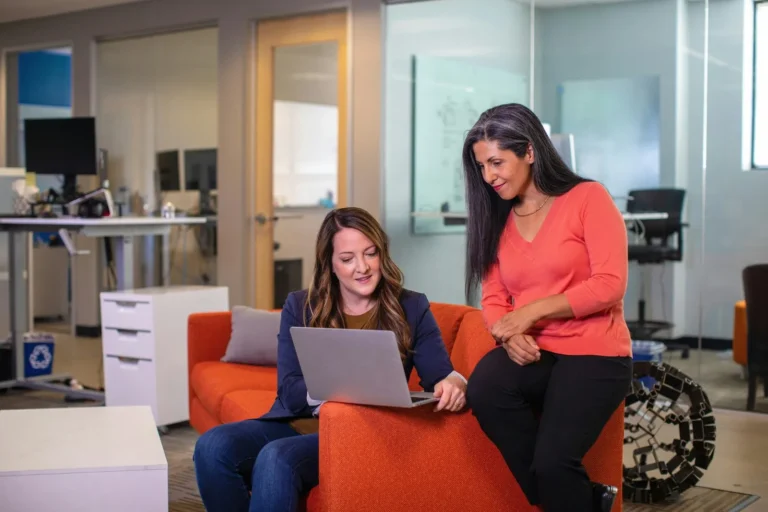 Duas mulheres conversando sobre consórcio de imóveis em frente a um notebook