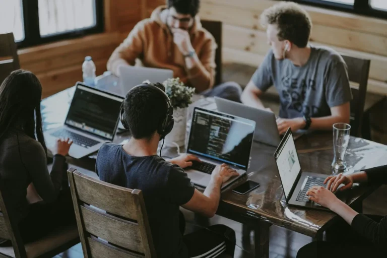 Pessoas trabalhando em notebooks em uma mesa compartilhada